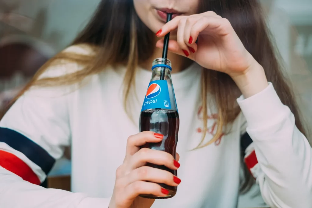 a woman with a straw drinking a bottle of soda